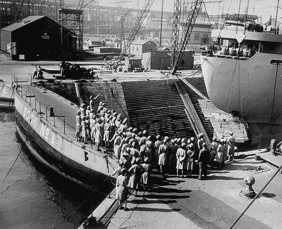 Image shows a group of women walking through a shipyard (image courtesy of the U.S. Army Signal Corps Photograph Collection, Library of Virginia)